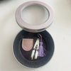 A pair of mini precision sewing scissors with a protective cover resting on a dark gray circular dish.