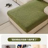 A light green patterned jacquard sofa cover displayed on a beige sectional sofa, with various accessories nearby.