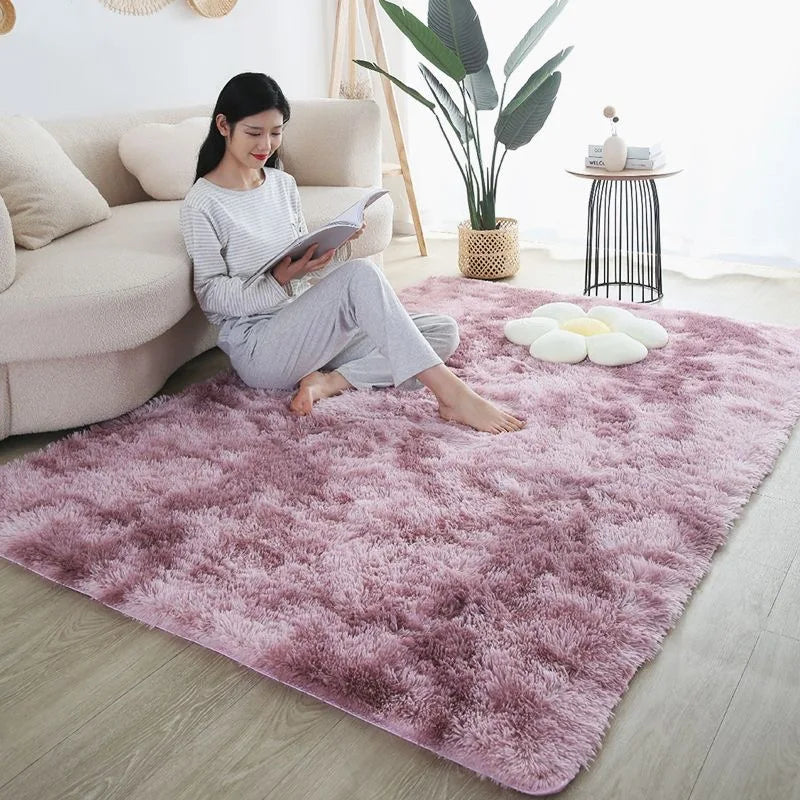 A pink faux fur rug is placed on a light wood floor in a living room setting with a woman reading.