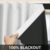 A hand is pulling a white blackout window curtain across a black fabric panel.