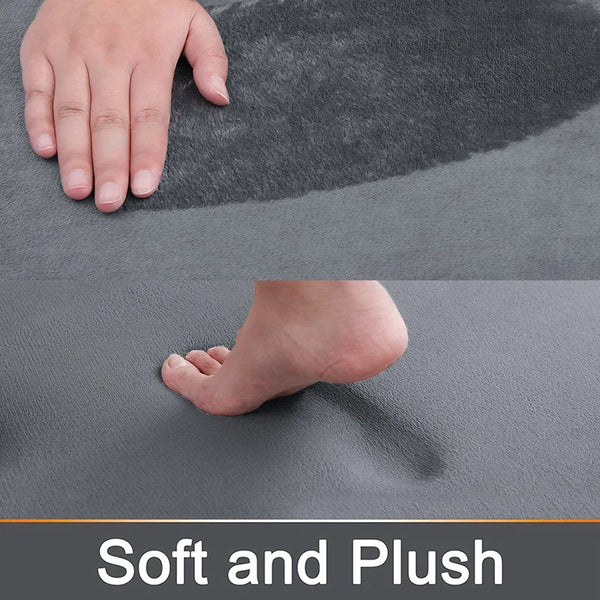 Close-up view of a gray memory foam bathroom mat showing a hand and a bare foot pressing into the soft surface.