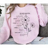 Pink sweatshirt featuring black script text about being beautiful and strong with a flower design