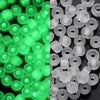 A close-up view of small, round, translucent green glow-in-the-dark glass seed beads.