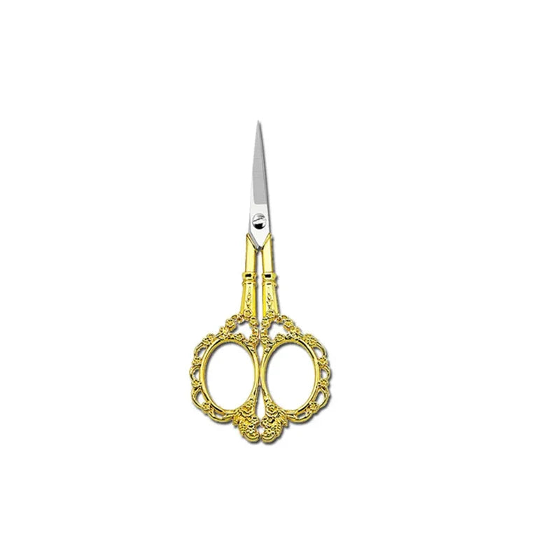 A pair of gold-colored crafting scissors with a silver blade and ornate handles.