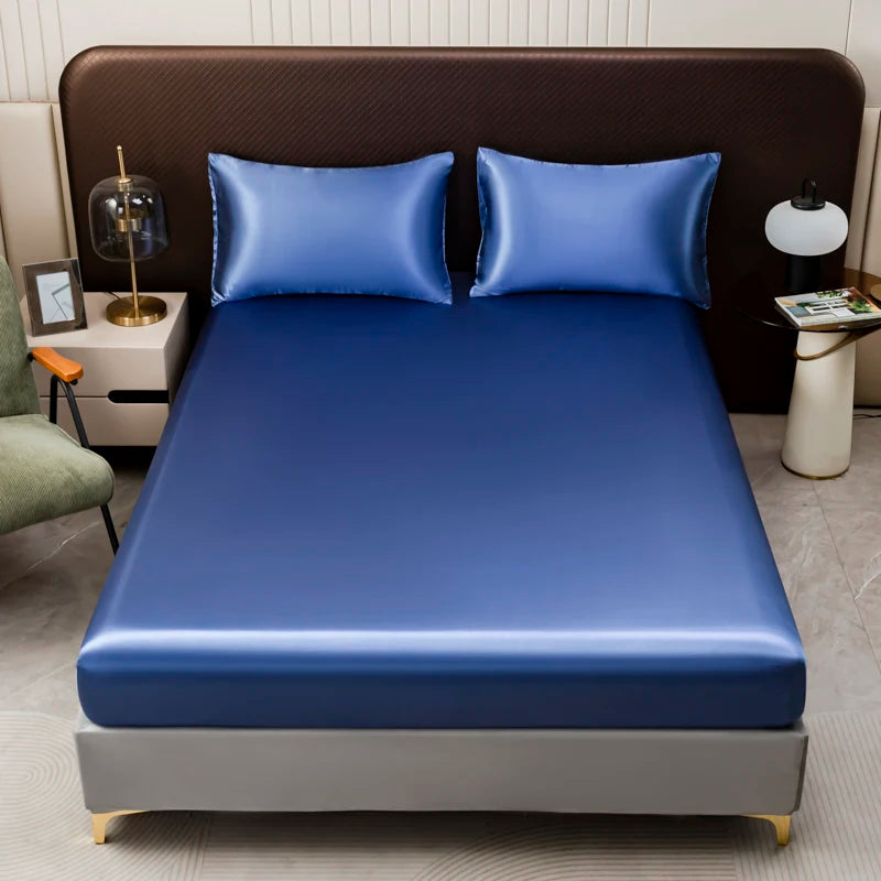 A blue satin bedding set displayed on a bed with dark brown headboard and pillows.