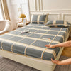 A fitted sheet set in gray and beige stripes is laid out on a bed with pillows.