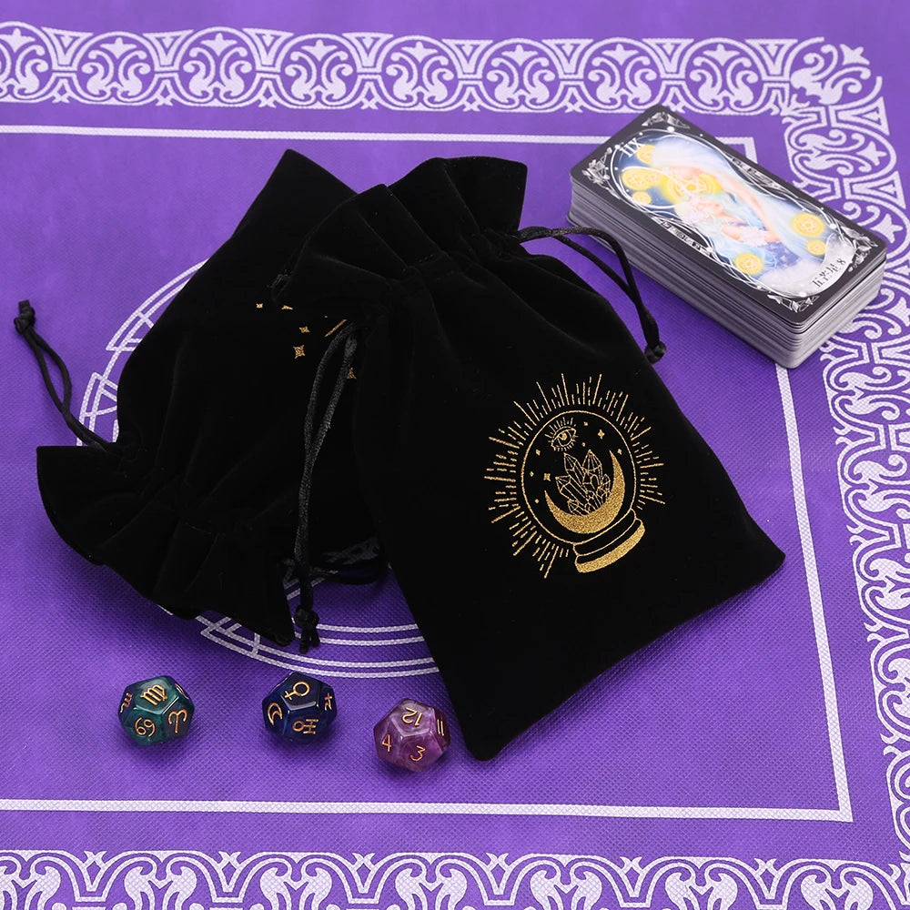 A black velvet tarot cards storage pouch with gold sun design and several tarot cards on a purple patterned surface.