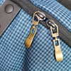 Gold-toned replacement metal zipper pulls attached to a dark fabric strap.
