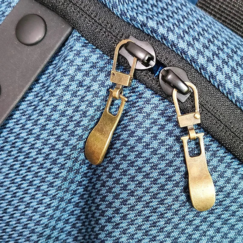 Gold-toned replacement metal zipper pulls attached to a dark fabric strap.