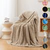 A beige soft flannel throw blanket draped on a light-colored sofa next to decorative fabric swatches.