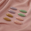 Eight plastic safety pins in various pastel shades of pink, green, and yellow arranged on a pink fabric.