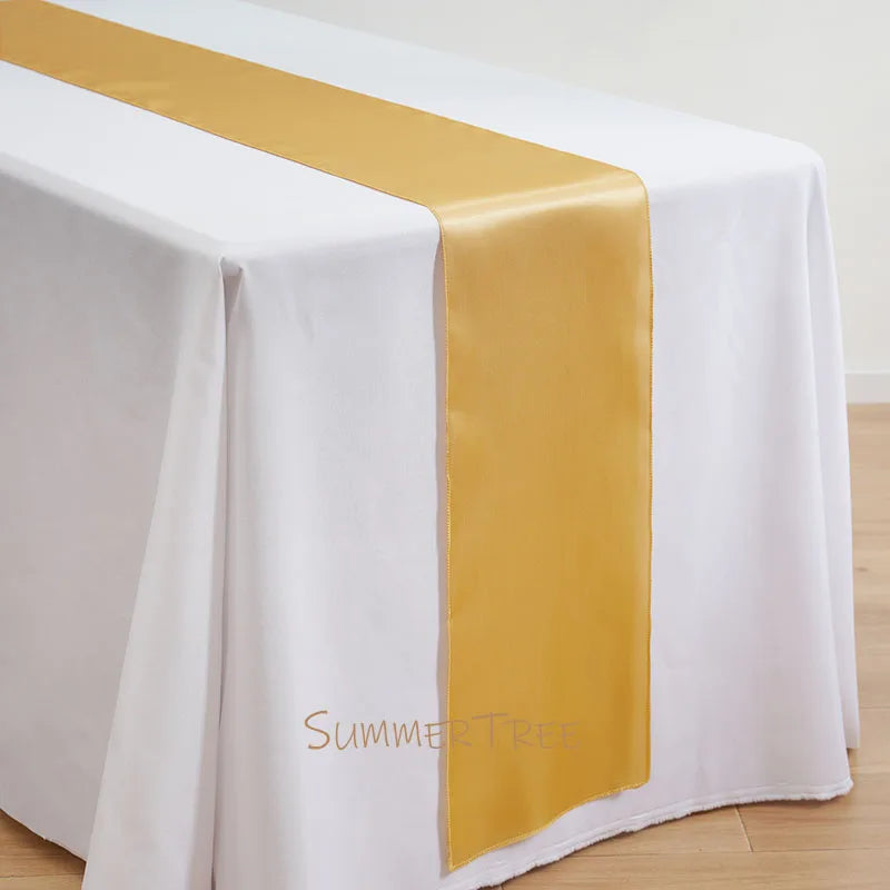 Elegant satin gold table runner draped across a white tablecloth.
