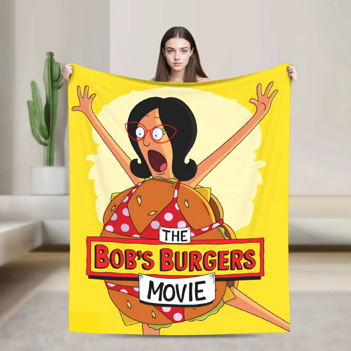 A yellow throw blanket featuring a cartoon character with large glasses and an open mouth surrounded by a light yellow circle