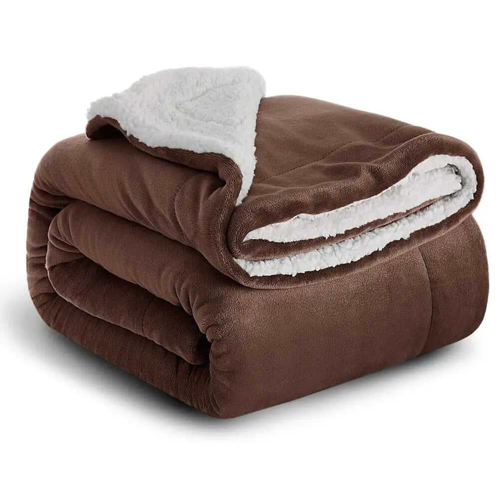 A dark brown sherpa fleece blanket rolled up, showing a white fluffy lining.