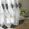 Gold embroidered gauze curtain with blue accents hanging in a window
