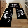 Three black kitchen mats with white cutlery designs placed on a light wood floor.