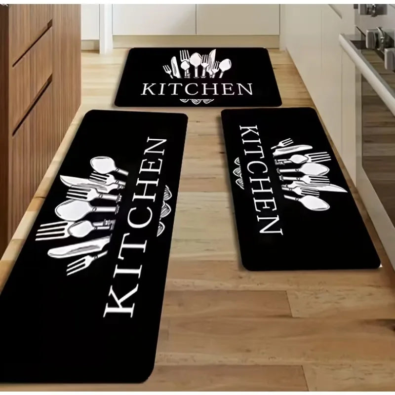 Three black kitchen mats with white cutlery designs placed on a light wood floor.