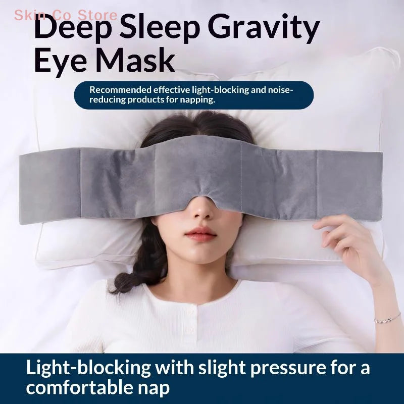 A woman is wearing a gray eye mask designed for deep sleep and light blocking while resting on a white pillow.
