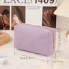 A lavender textured cosmetic storage pouch with a gold zipper is displayed on a white surface.