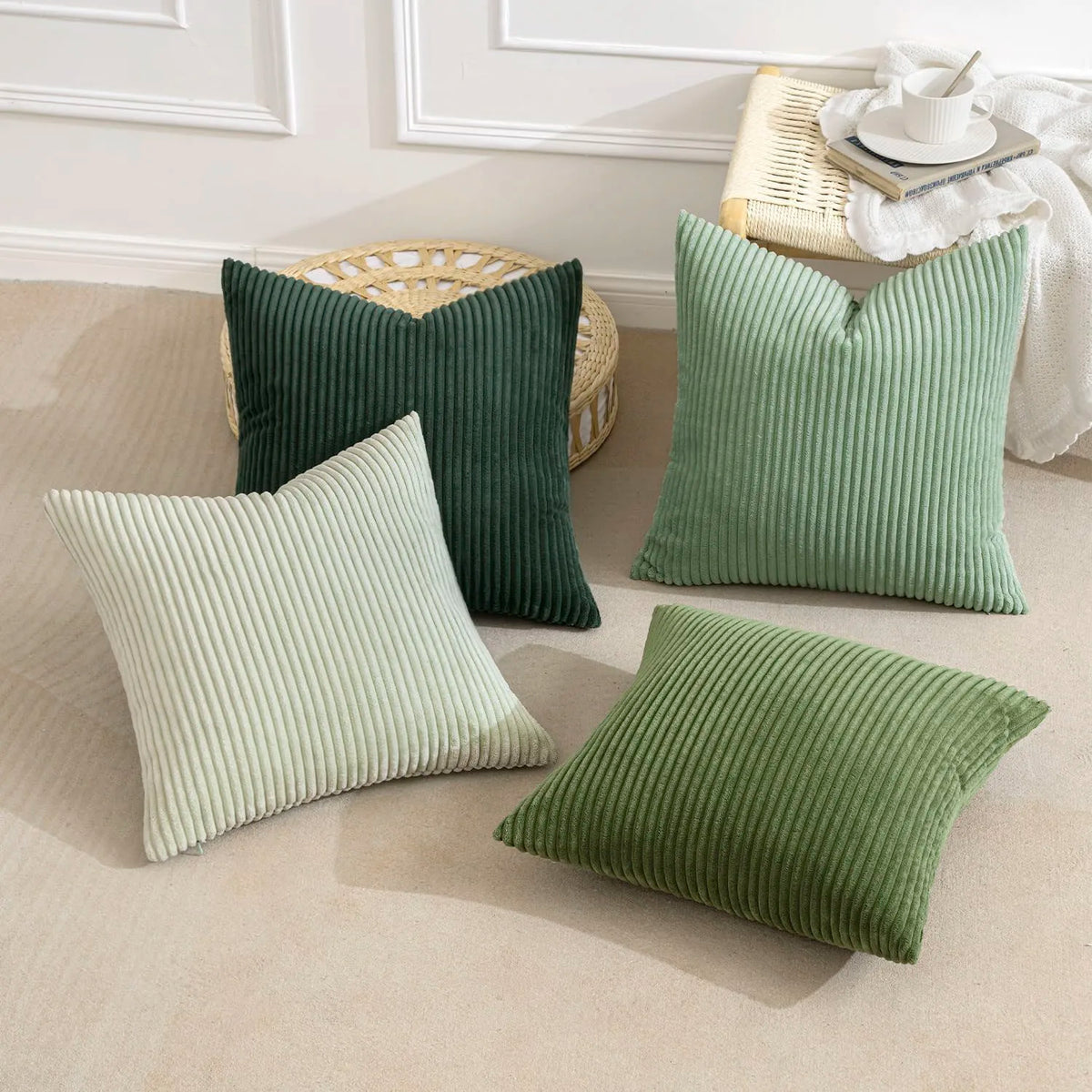 A set of four textured throw pillows in shades of olive green and sage green on a light beige sofa.
