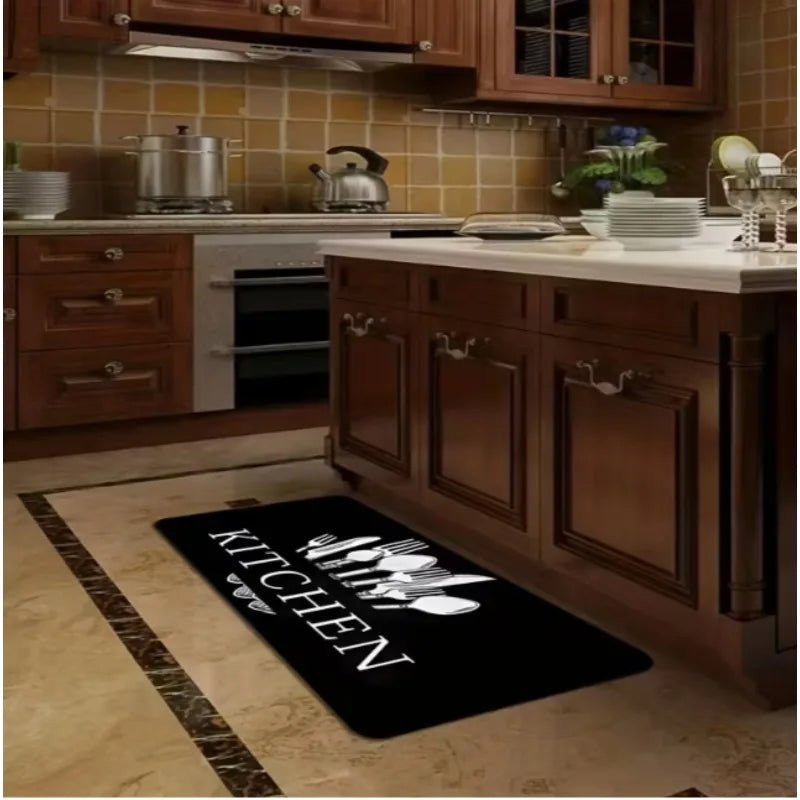 A black non-slip flannel area rug with white silhouette designs placed on a light wood floor in a kitchen setting.