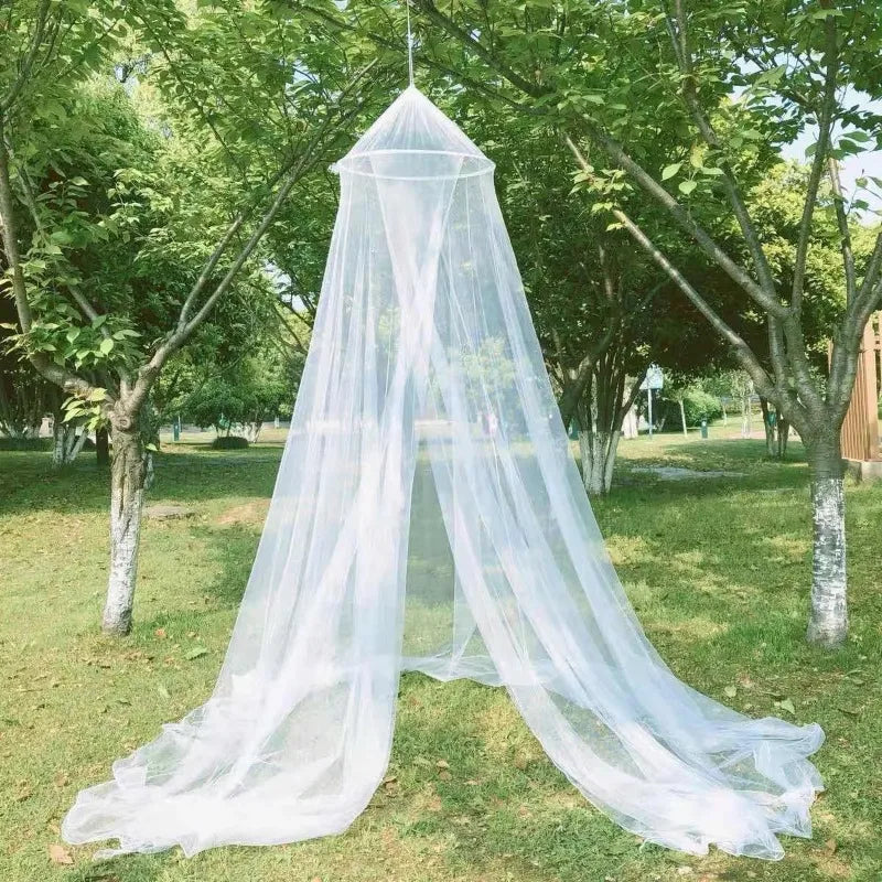 A large white dome mosquito net is suspended outdoors in a grassy area.