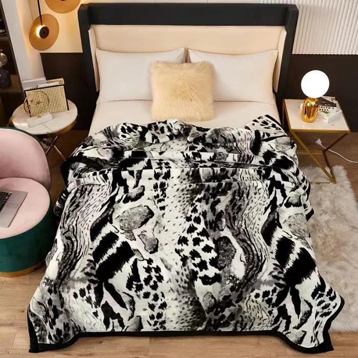 A black and white patterned plush mink fleece king size blanket displayed on a bed.
