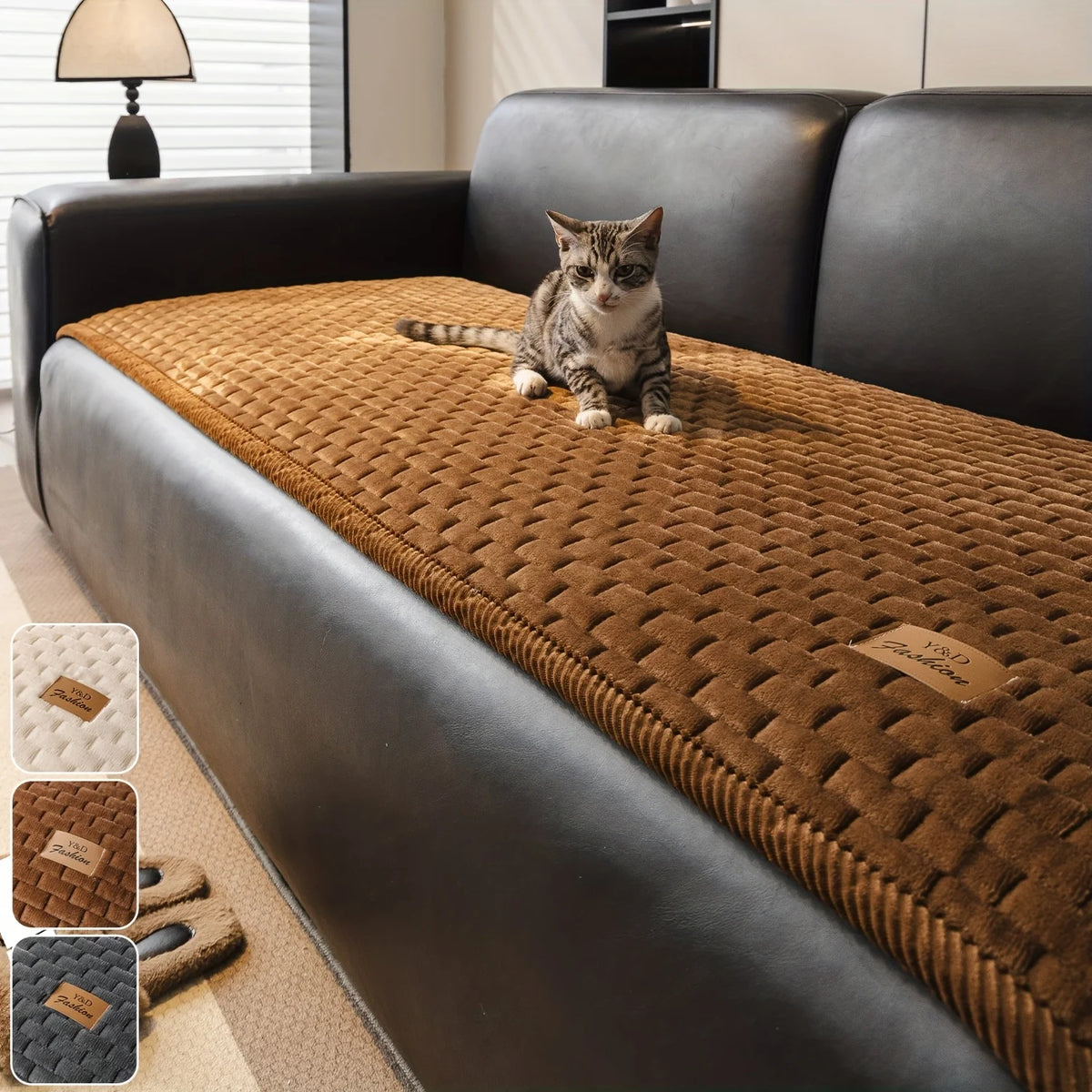 A tabby cat sitting on a brown quilted sofa cover in a modern living room setting.