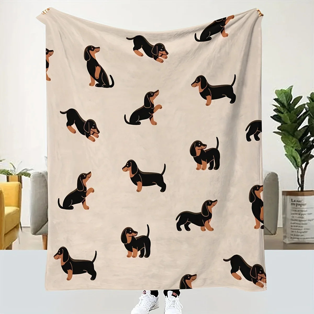 A beige flannel blanket featuring a repeating pattern of black dachshund silhouettes.