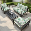 A dark outdoor sofa set with light green and white floral leaf cushion covers placed on a wooden deck.
