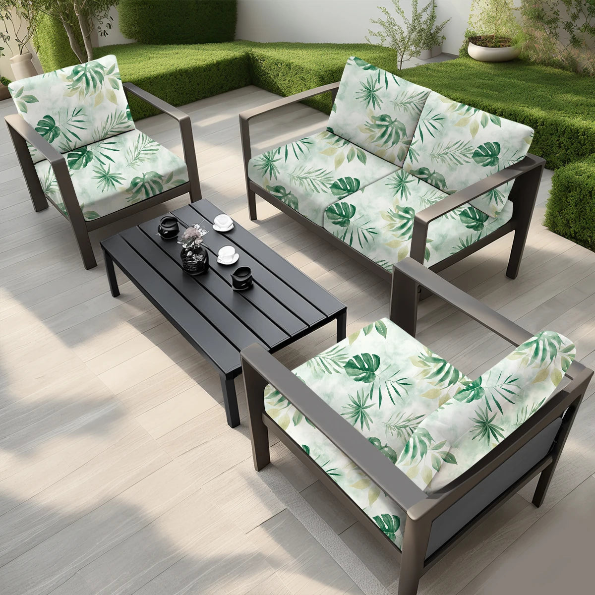 A dark outdoor sofa set with light green and white floral leaf cushion covers placed on a wooden deck.