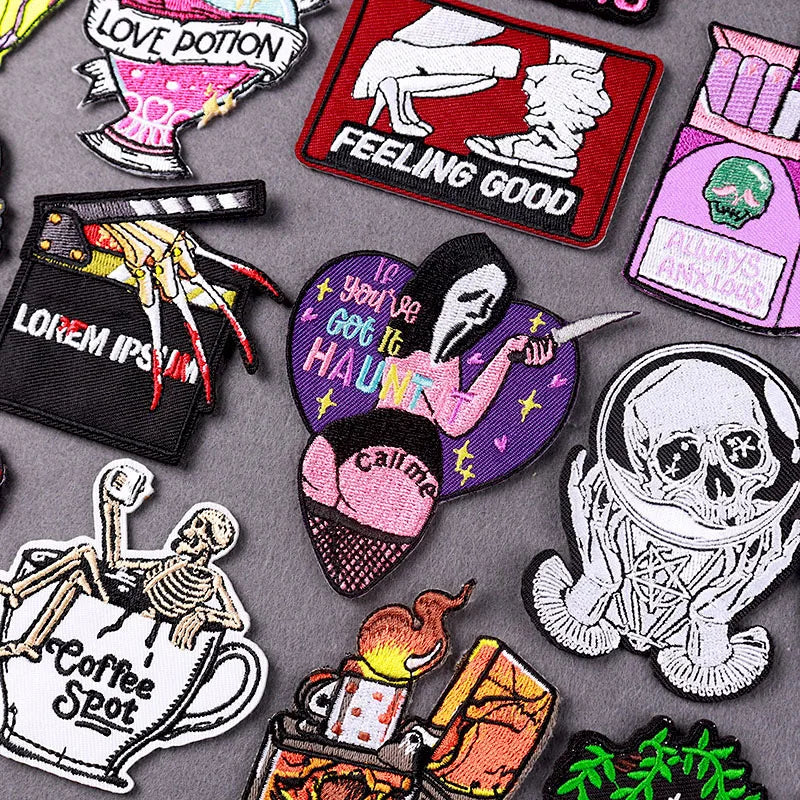 A collection of embroidered horror movie patches featuring skulls, potions, and spooky designs on gray fabric.