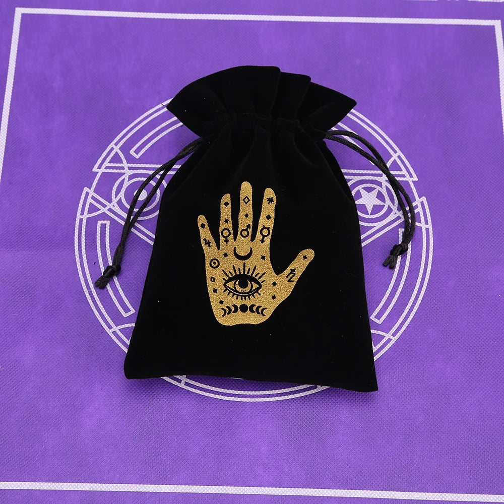 Black velvet pouch with a gold hand symbol resting on a purple background.