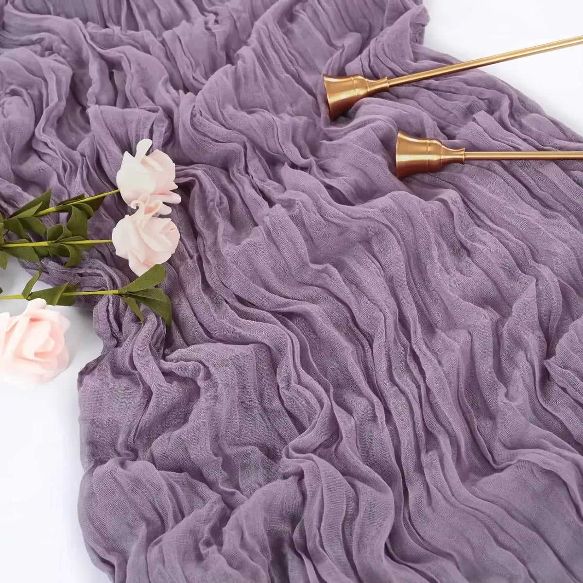 A purple ruffled gauze table runner with gold-toned decorative spoons and pink roses.