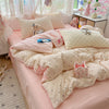 A pink polka dot duvet cover set with matching pillowcases and stuffed animal toys on a bed.