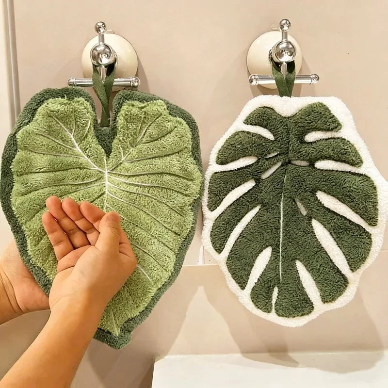 A hand towel with an embroidered leaf design hanging on a rack.