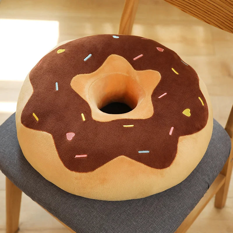 A brown and orange plush pillow shaped like a frosted doughnut with colorful sprinkles.