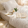 Pure white princess ruffle cotton bedding set with pillows and a book on a bed