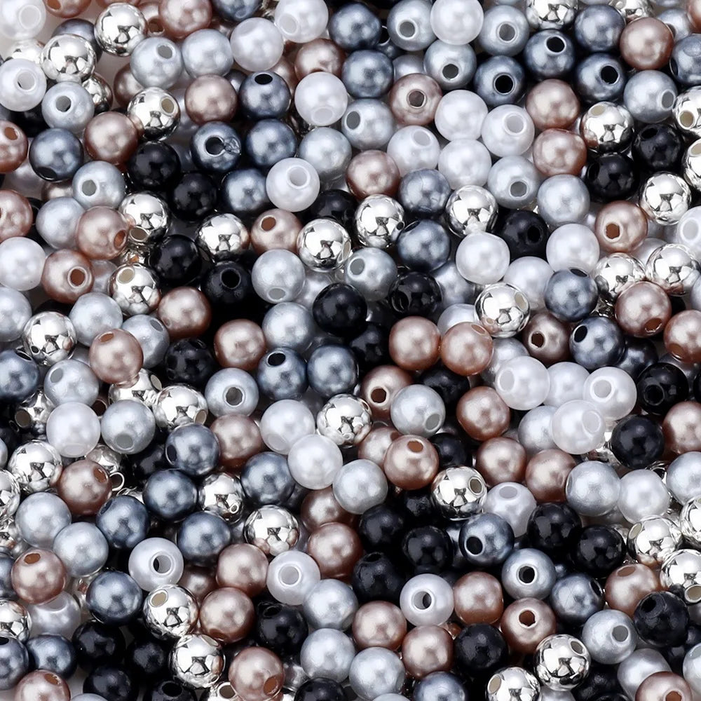 A close-up of various imitation pearl beads in shades of silver, gray, black, and rose gold.