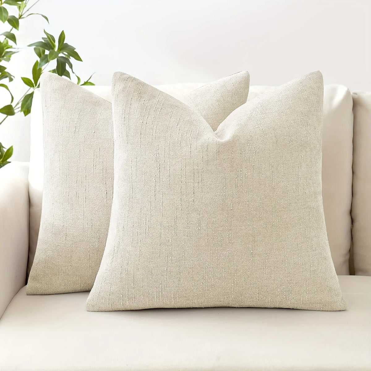 A beige linen textured throw pillow resting on a light-colored sofa.