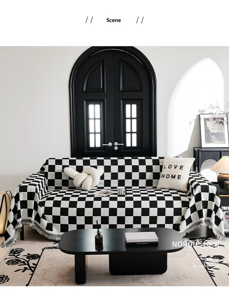 A black and white checkerboard sofa slipcover displayed in a bright room with a dark wooden door.