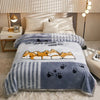 A gray and white striped plush blanket with a happy growth paw print design is displayed on a bed.