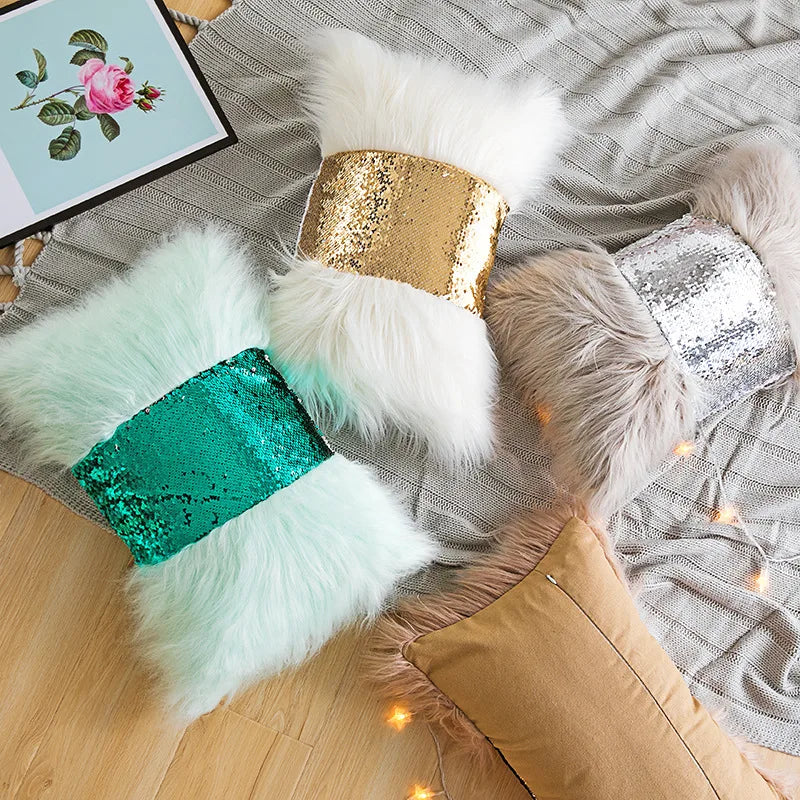 A collection of fluffy cushions covered in gold, white, and teal sequins resting on a gray fabric.
