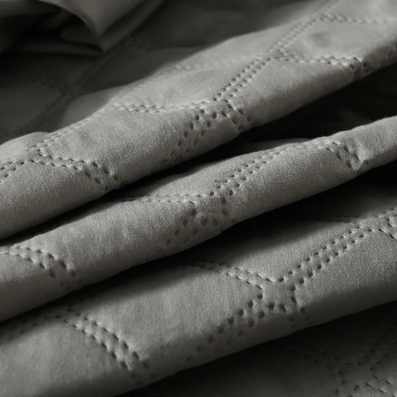 Close-up of a gray waterproof quilted mattress protector fabric texture.
