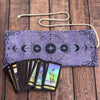 A purple tarot card storage pouch with a mystical tree of life design and several tarot cards inside.