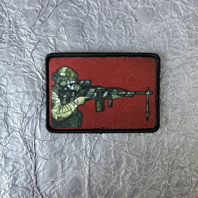 A red tactical patch featuring a silhouette of a skull wearing a helmet aiming a rifle.