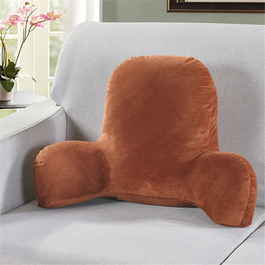 A plush, brown lumbar support cushion with arms resting on a light gray sofa.