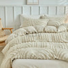 A beige embossed floral duvet cover set with matching pillows on a white bed.