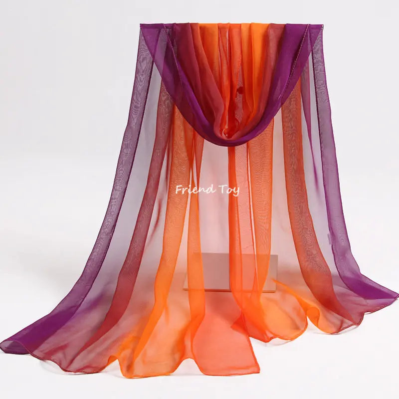 A sheer, flowing scarf in shades of purple, orange, and pink draped for sensory play.