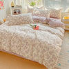A floral printed bedding set featuring soft pink and beige tones on a bed with white blinds.